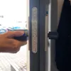 A hand is holding a black electronic lock device and is about to insert it into a silver door lock mechanism. Podgląd zdjęcia produktu