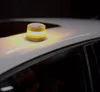 A yellow and white emergency light is placed on the roof of a white car. Produktbild-Vorschau