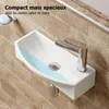 A small, white wall-mounted sink with a chrome faucet, set against a tiled wall. Produktbild-Vorschau