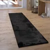 A black shaggy rug is laid out on a light wooden floor in a room with natural light coming from a large window or glass door. Anteprima dell’immagine prodotto