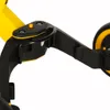 A close-up view of the black and yellow frame and wheel mechanism of a children's trike. Podgląd zdjęcia produktu