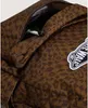 Close-up of a brown backpack with a leopard and checkered pattern, showing a zippered pocket with an item inside and a Vans logo patch. Podgląd zdjęcia produktu