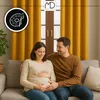A pregnant couple sitting on a couch in front of yellow curtains. Produktbild-Vorschau