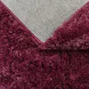 Close-up view of the underside and fluffy texture of a burgundy rug. Produktbild-Vorschau