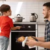 A father and son are in a kitchen, with the son operating the oven controls while the father holds a tray of croissants. Produktbild-Vorschau