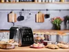 A kitchen counter with a bread maker and various baked goods, including cupcakes and bread rolls. Podgląd zdjęcia produktu