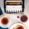 A toaster with toast, a cup of tea, and jam on a marble countertop. Anteprima dell’immagine prodotto