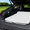 An inflatable mattress is laid out in the open trunk of a car, parked in a grassy outdoor area with trees in the background. Voir les images du produit