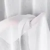 A hand is holding a sheer white fabric, likely a curtain, with folds and texture visible. Náhled obrázku produktu