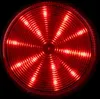 A close-up, circular shot of a red LED light with concentric rings and radial light patterns against a black background. Produktbild-Vorschau