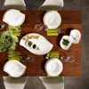 A dining table set for a meal with white plates, cutlery, and a green centerpiece. Náhľad obrázku produktu