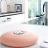 A pink hot water bottle is placed on a white countertop in a modern kitchen. Produktbild-Vorschau