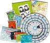 A collection of game components, including cards, a circular game board, and maps, are spread out on a white surface. Produktbild-Vorschau