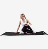 A woman is doing a yoga pose on a black yoga mat. Náhľad obrázku produktu
