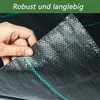 A hand is holding a piece of black fabric with green stitching, showing its texture and durability. Voir les images du produit