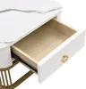 Close-up of an open drawer on a white table with a marble-like pattern. Voir les images du produit