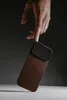 A hand is about to drop a phone case onto a surface. Produktbild-Vorschau