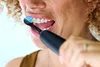 Close-up of a person brushing their teeth with an electric toothbrush. Produktbild-Vorschau