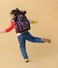 A young girl wearing a backpack and colorful sweater is captured mid-motion against a plain background. Náhľad obrázku produktu