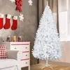 A white artificial Christmas tree stands in a room decorated for Christmas, with stockings hanging on the wall and a chest of drawers. Podgląd zdjęcia produktu
