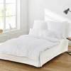A neatly made bed with white bedding in a bright room. Produktbild-Vorschau