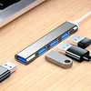 A silver USB hub with four blue USB 3.0 ports is shown on a wooden surface, connected to a laptop. Several USB drives and cables are also visible. Produktbild-Vorschau