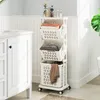 A white laundry cart with three baskets is shown in a bathroom setting next to a white vanity. Produktbild-Vorschau