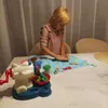 A young girl is playing with a toy dough set on a table. Anteprima dell’immagine prodotto