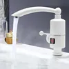 A white electric hot water tap is shown in a bathroom or kitchen setting, with water flowing into a sink. Náhled obrázku produktu