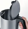 A hand is holding the handle of a stainless steel electric kettle with the lid open. Produktbild-Vorschau