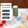 Two mini handheld vacuum machines are shown, one green and one white, on a table with some vegetables. A white card with text describing the features of the vacuum machine is on the left side of the image. Produktbild-Vorschau