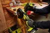 A person is using a Ryobi angle grinder to cut metal on a workbench. Produktbild-Vorschau