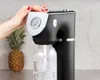 A hand is shown operating a black soda maker with a pressure gauge, with a pineapple in the background. Produktbild-Vorschau