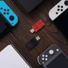 A flat lay of Nintendo Switch controllers and two USB adapters on a wooden surface. Voir les images du produit