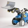 A toy tractor with a snow shovel attachment, filled with white material, on a white background with some snow on the ground. Produktbild-Vorschau
