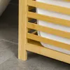 Close-up of the corner of a bamboo laundry basket with white fabric inside, resting on a tiled floor. Náhľad obrázku produktu
