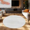 A living room scene with a round white rug in the foreground, a sofa with orange cushions, and a TV stand with a television. Produktbild-Vorschau