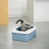 A gray cat is sitting in a blue and white litter box in a modern, clean room. Voir les images du produit