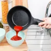 A hand is pouring red sauce from a black frying pan into a light blue bowl in a kitchen sink. Náhled obrázku produktu