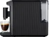 A black Tchibo coffee machine is shown in profile, with a glass of espresso in front of it. Produktbild-Vorschau