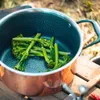 Broccoli florets are placed in a copper pot with a non-stick interior, set on a wooden surface outdoors. Produktbild-Vorschau