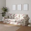 A floral-patterned sofa in a living room setting with a plant and framed pictures on the wall. Podgląd zdjęcia produktu