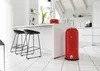 A modern white kitchen with a red pedal bin and two black bar stools. Anteprima dell’immagine prodotto