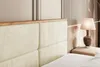 A close-up view of a bed's upholstered headboard and a bedside table with a lamp. Produktbild-Vorschau