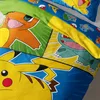A close-up view of Pokemon-themed bedding, featuring characters like Pikachu, Charmander, and Bulbasaur. Produktbild-Vorschau