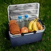 A picnic basket filled with food and drinks sitting on grass. Voir les images du produit