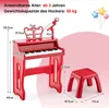 A red toy piano with a microphone and stool, with dimensions indicated by lines and text. Podgląd zdjęcia produktu