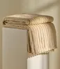 A folded blanket with a ribbed texture is displayed on a white surface. Produktbild-Vorschau