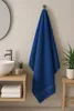 A blue towel hanging on a hook in a bathroom. Produktbild-Vorschau