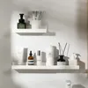 Two white shelves mounted on a white wall, displaying various bathroom products. Voir les images du produit